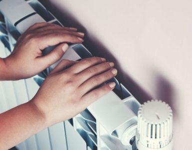 Un enfant se chauffe les mains sur le radiateur de la maison