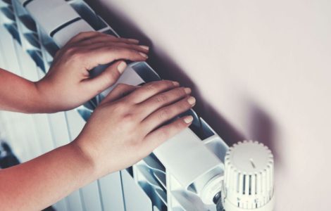 Un enfant se chauffe les mains sur le radiateur de la maison