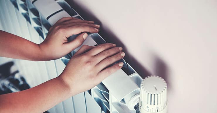 Un enfant se chauffe les mains sur le radiateur de la maison