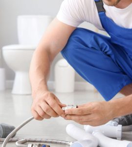 Un homme en combinaison bleue préparation l'installation sanitaire dans une salle de bains