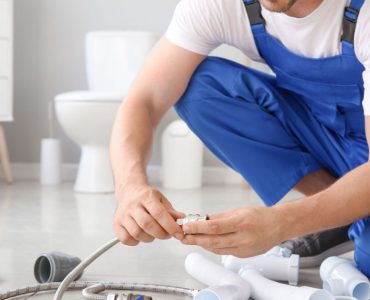 Un homme en combinaison bleue préparation l'installation sanitaire dans une salle de bains