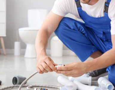 Un homme en combinaison bleue préparation l'installation sanitaire dans une salle de bains