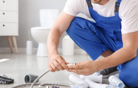 Un homme en combinaison bleue préparation l'installation sanitaire dans une salle de bains