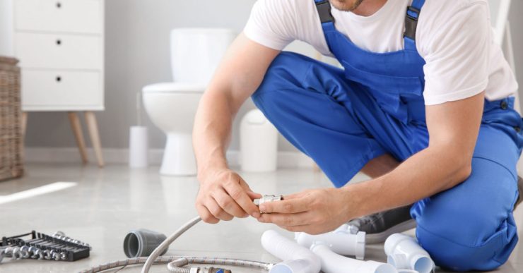 Un homme en combinaison bleue préparation l'installation sanitaire dans une salle de bains