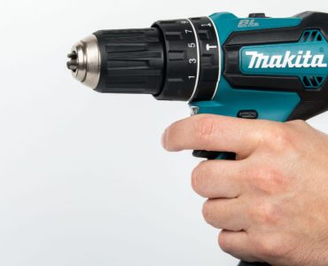 Zoom sur la main d’un homme tenant une perceuse électrique