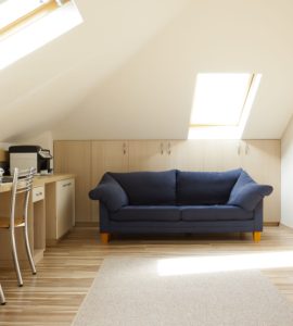 Une chambre aménagée dans le grenier avec un canapé bleu et un coin bureau
