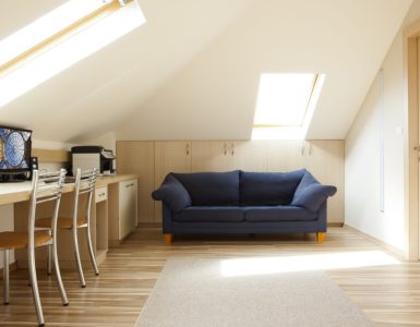 Une chambre aménagée dans le grenier avec un canapé bleu et un coin bureau