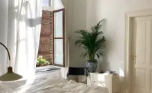 Vue sur une chambre aux tons blancs et une suspension en rotin