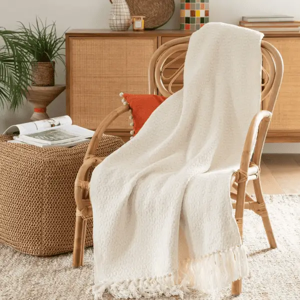 Un plaid en coton écru à poser sur canapé foncé ou sur le lit dans une chambre peu éclairée