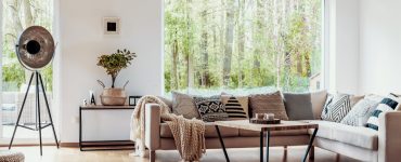 Salon avec canapé beige, parquet en bois et grandes baies vitrées
