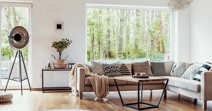 Salon avec canapé beige, parquet en bois et grandes baies vitrées