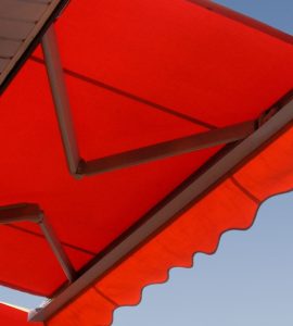 Une lampe murale allumée, placée sous un store banne