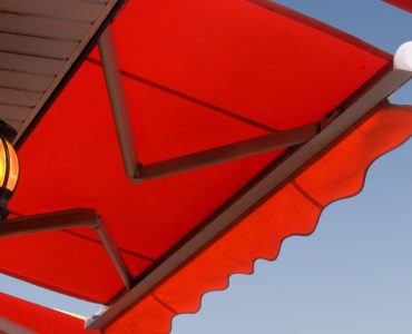 Une lampe murale allumée, placée sous un store banne