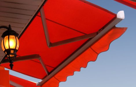 Une lampe murale allumée, placée sous un store banne