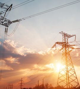 Des lignes électriques à haute tension avec le soleil couchant en fond