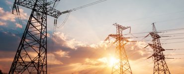 Des lignes électriques à haute tension avec le soleil couchant en fond