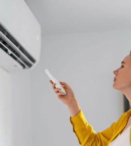 Une femme pointe une télécommande vers la climatisation
