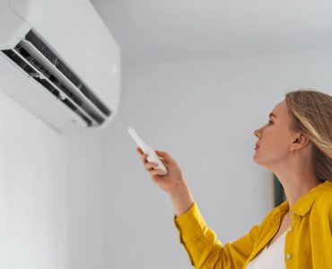 Une femme pointe une télécommande vers la climatisation