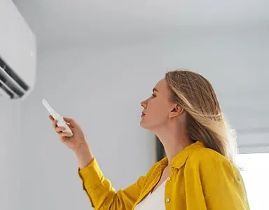 Une femme pointe une télécommande vers la climatisation