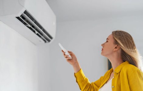 Une femme pointe une télécommande vers la climatisation
