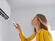 Une femme pointe une télécommande vers la climatisation