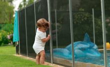 Un bébé s'appuyant sur une clôture de piscine