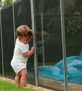 Un bébé s'appuyant sur une clôture de piscine