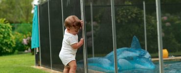 Un bébé s'appuyant sur une clôture de piscine