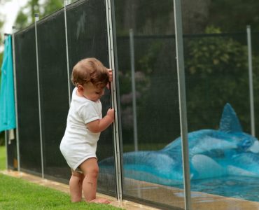 Un bébé s'appuyant sur une clôture de piscine