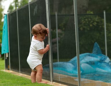 Un bébé s'appuyant sur une clôture de piscine