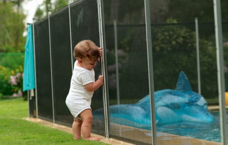 Un bébé s'appuyant sur une clôture de piscine