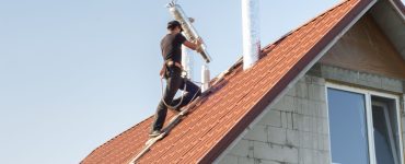 Un homme installe un conduit d'aération sur le toit