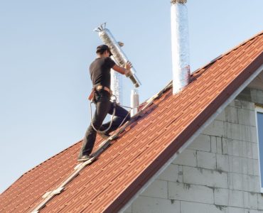 Un homme installe un conduit d'aération sur le toit