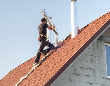 Un homme installe un conduit d'aération sur le toit