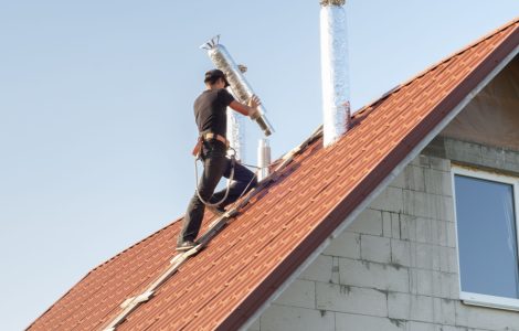 Un homme installe un conduit d'aération sur le toit