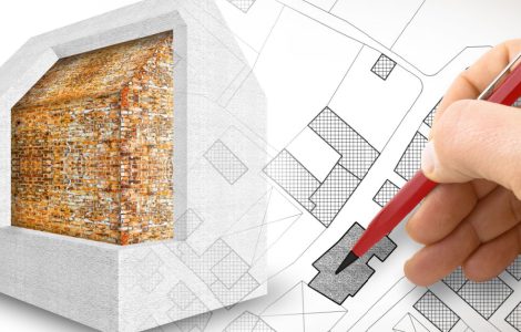 Zoom sur la main d'un homme tenant un crayon et dessinant le plan d'isolation thermique d'une maison