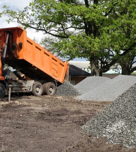 Un camion-benne déverse du gravier sur le chantier