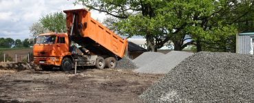 Un camion-benne déverse du gravier sur le chantier