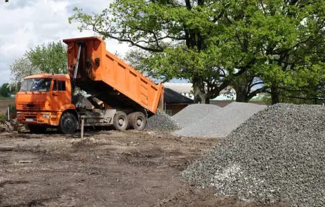Un camion-benne déverse du gravier sur le chantier