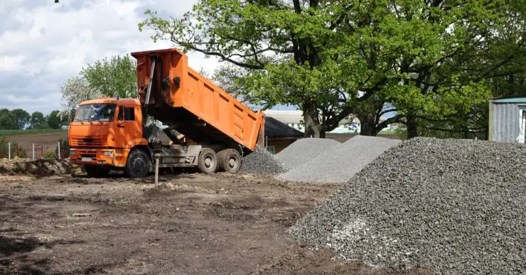 Un camion-benne déverse du gravier sur le chantier