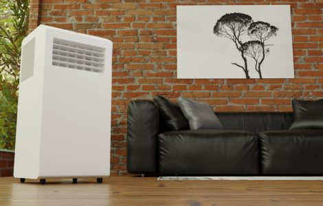 Un climatiseur mobile posé près d'un canapé en cuir noir