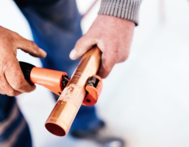 Zoom sur les mains d'un homme coupant un tuyau en cuivre avec un coupe-tuyau