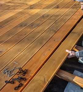 Un homme installant le sol en bois d'une terrasse
