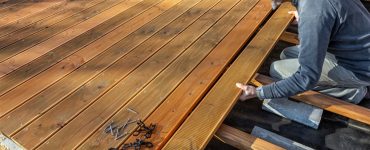 Un homme installant le sol en bois d'une terrasse