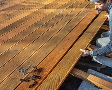 Un homme installant le sol en bois d'une terrasse