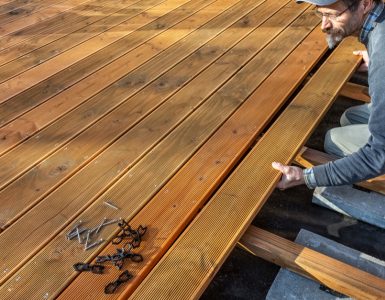 Un homme installant le sol en bois d'une terrasse