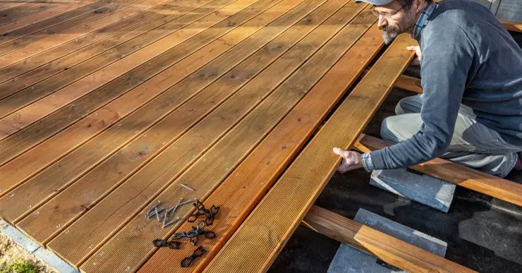 Un homme installant le sol en bois d'une terrasse