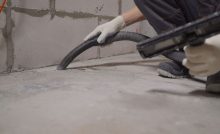 Un homme en gants blancs nettoie le sol avec un aspirateur après le chantier