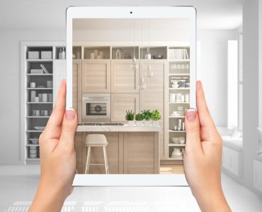 Mains tenant une tablette montrant une cuisine moderne blanche et en bois