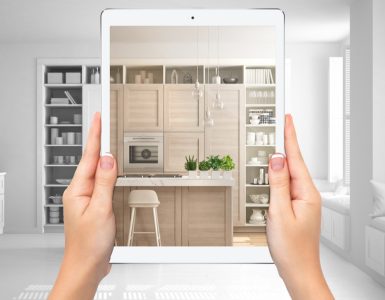 Mains tenant une tablette montrant une cuisine moderne blanche et en bois